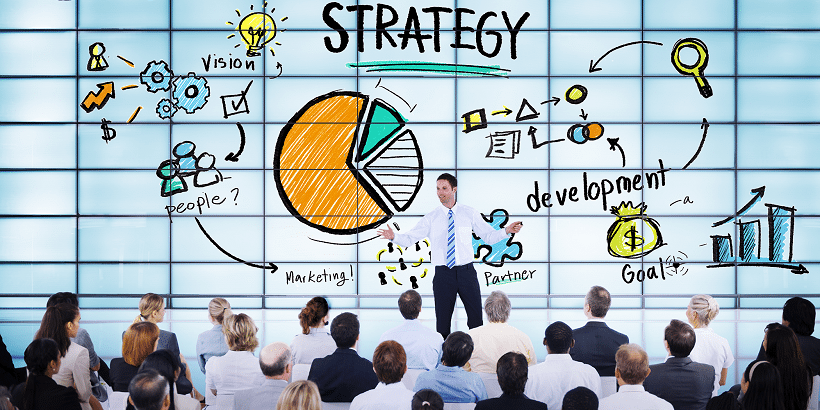 Man giving management presentation in front of a large whiteboard.