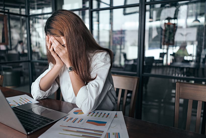 Woman looking upset sitting at desk in work office. 