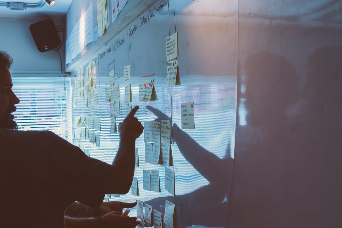 Man pointing at sticky notes on a whiteboard. 